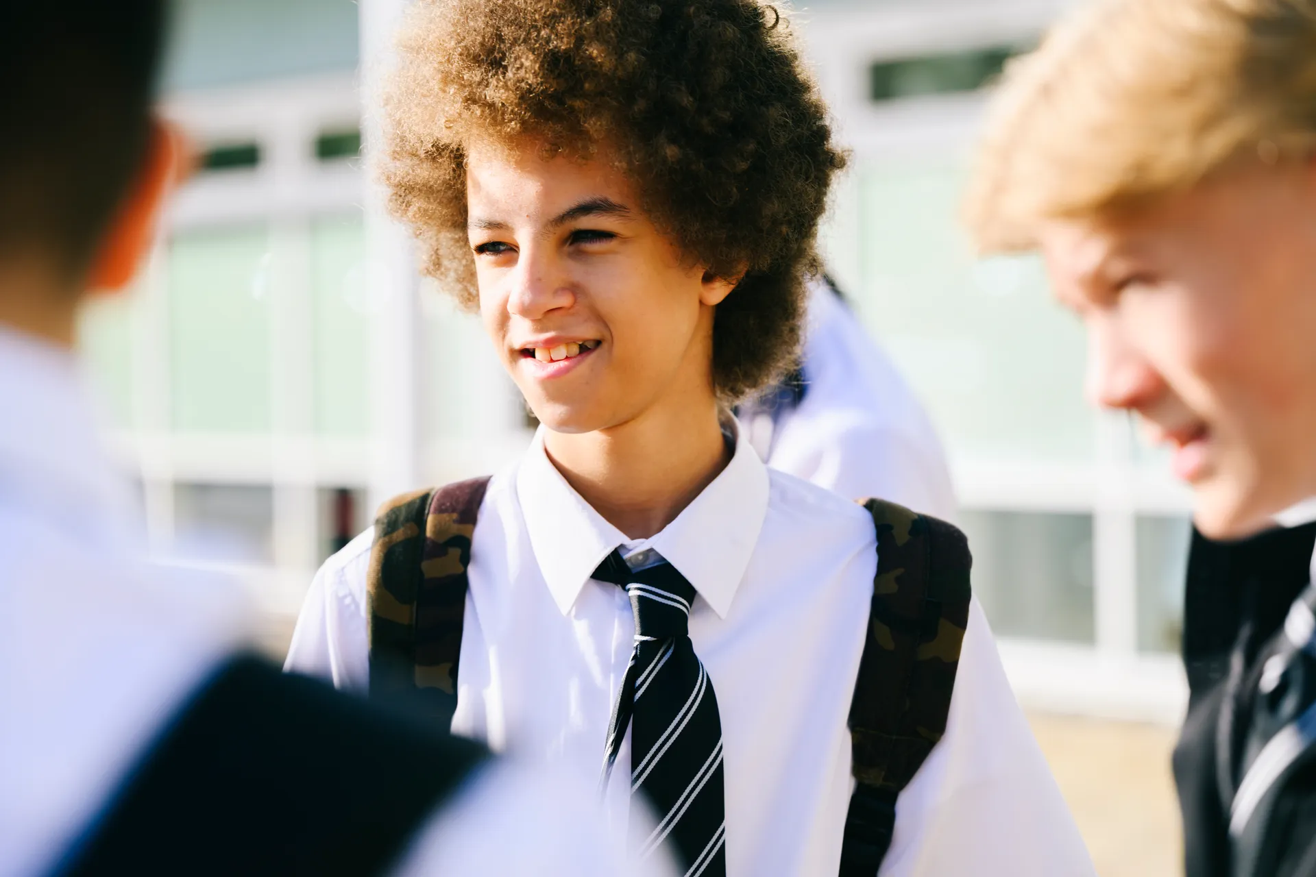 Vaughan College student with afro hair laughing with friends in school uniform with striped tie