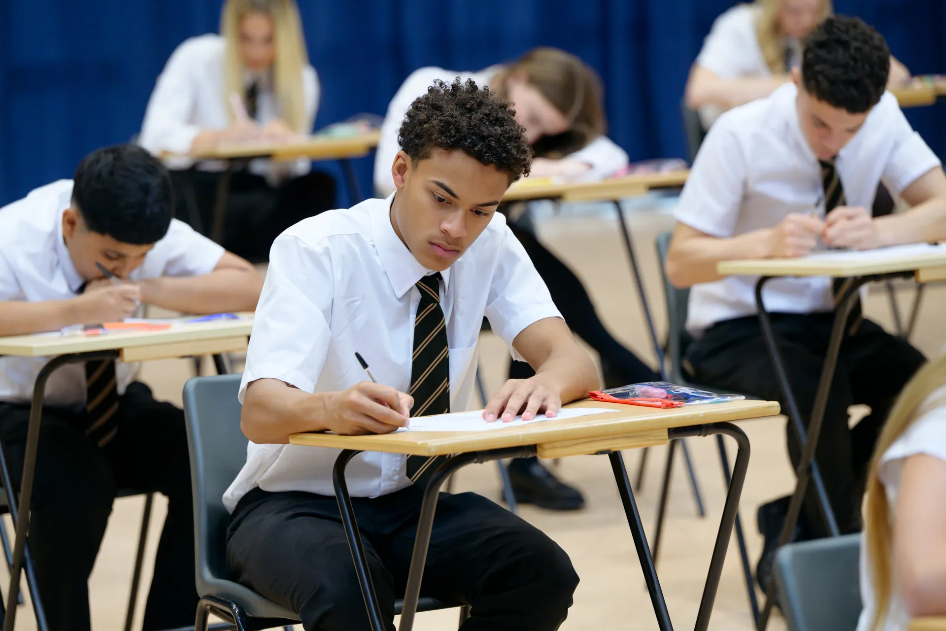 A Vaughan College student concentrating while writing at a desk during an exam
