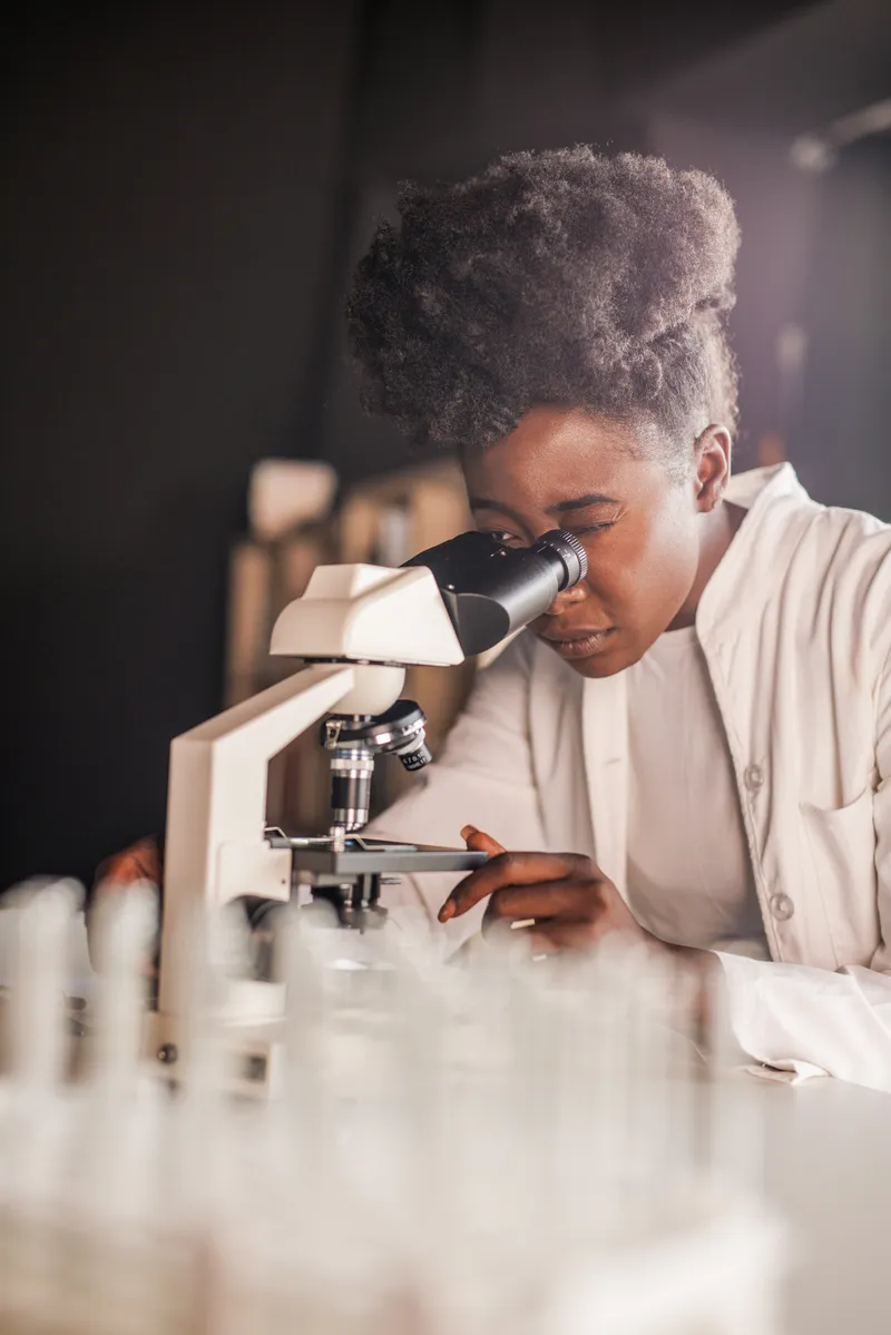 A student looking through a microscope in a biology lab