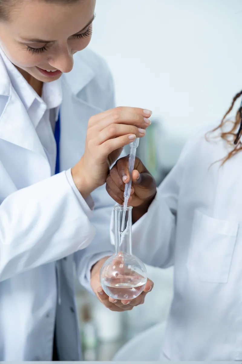 A student using a pipette and flask in a chemistry lab