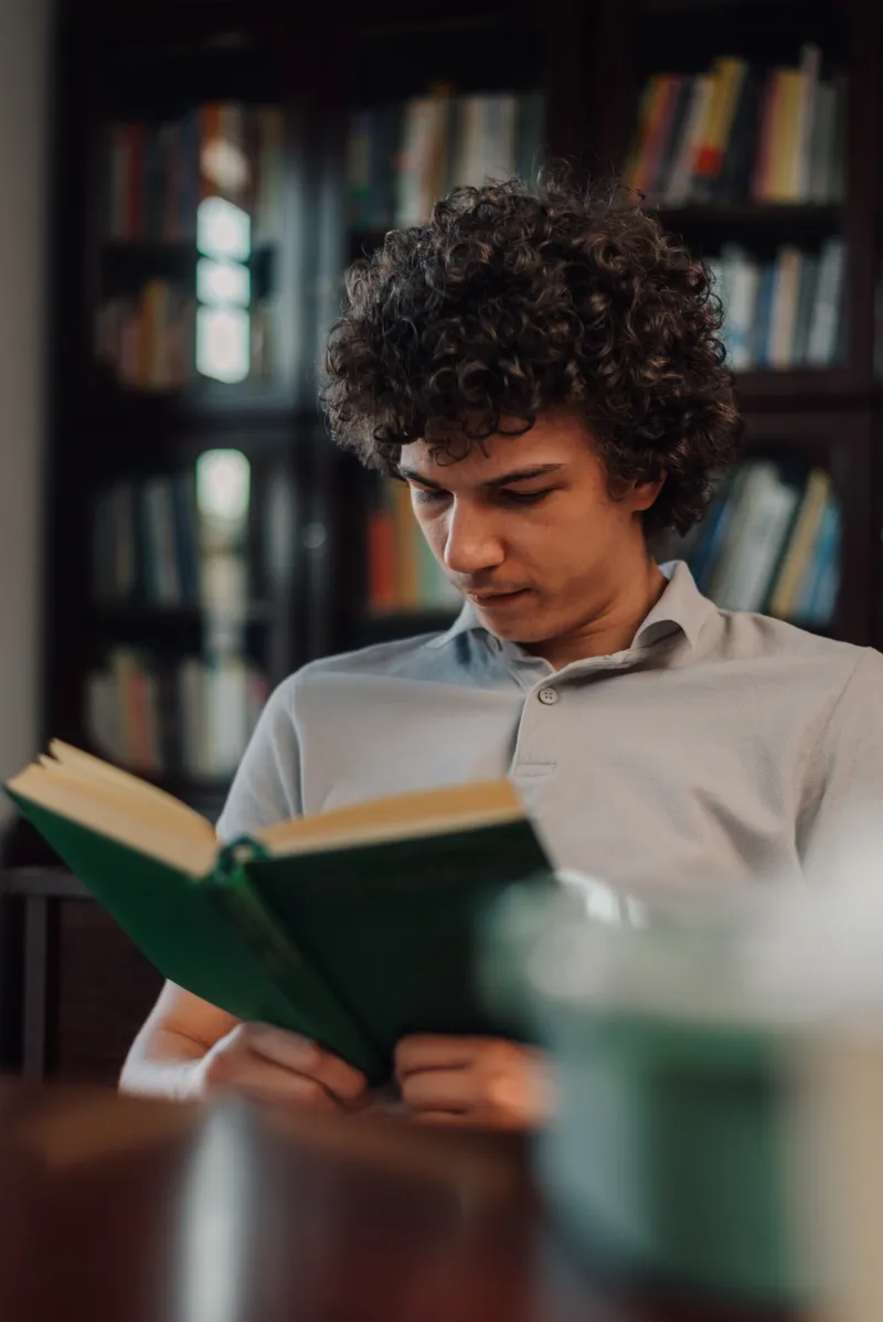 A student reading in a wood-panelled library
