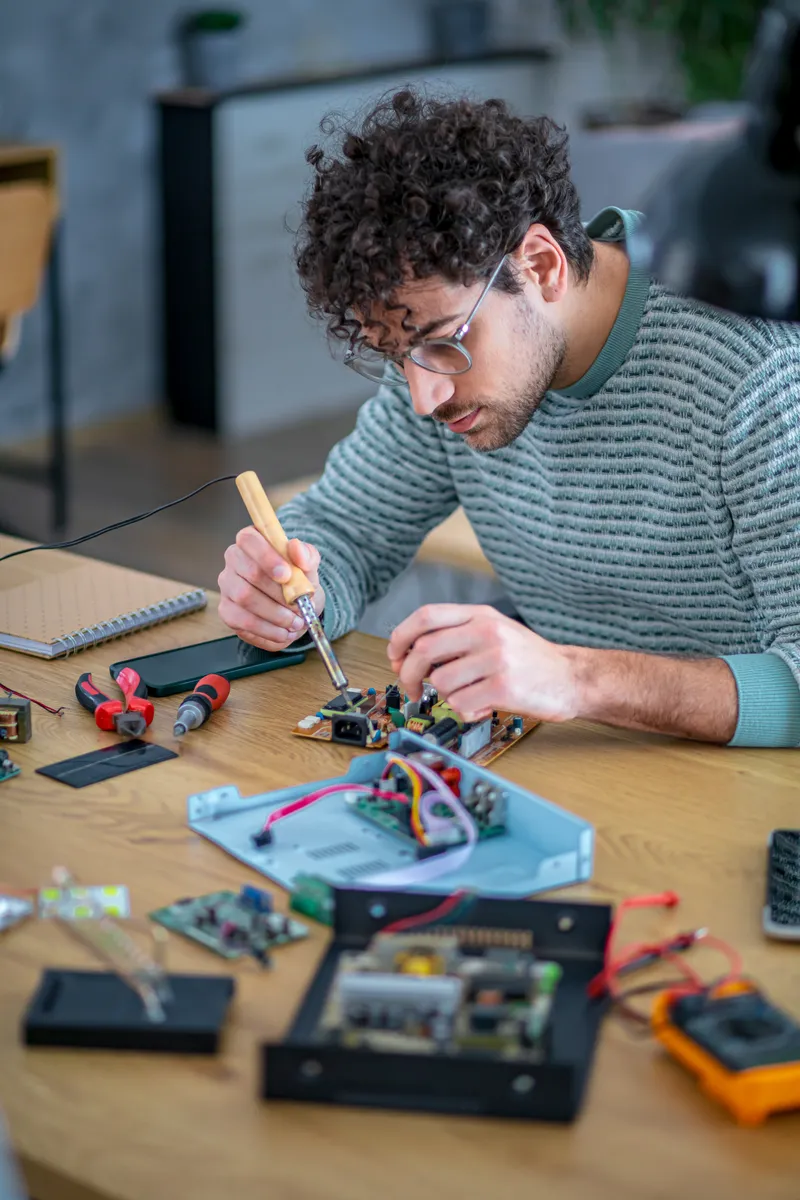 A student building an electronic circuit at a workbench