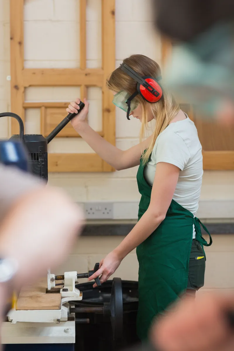 A student working at a lathe wearing ear protection