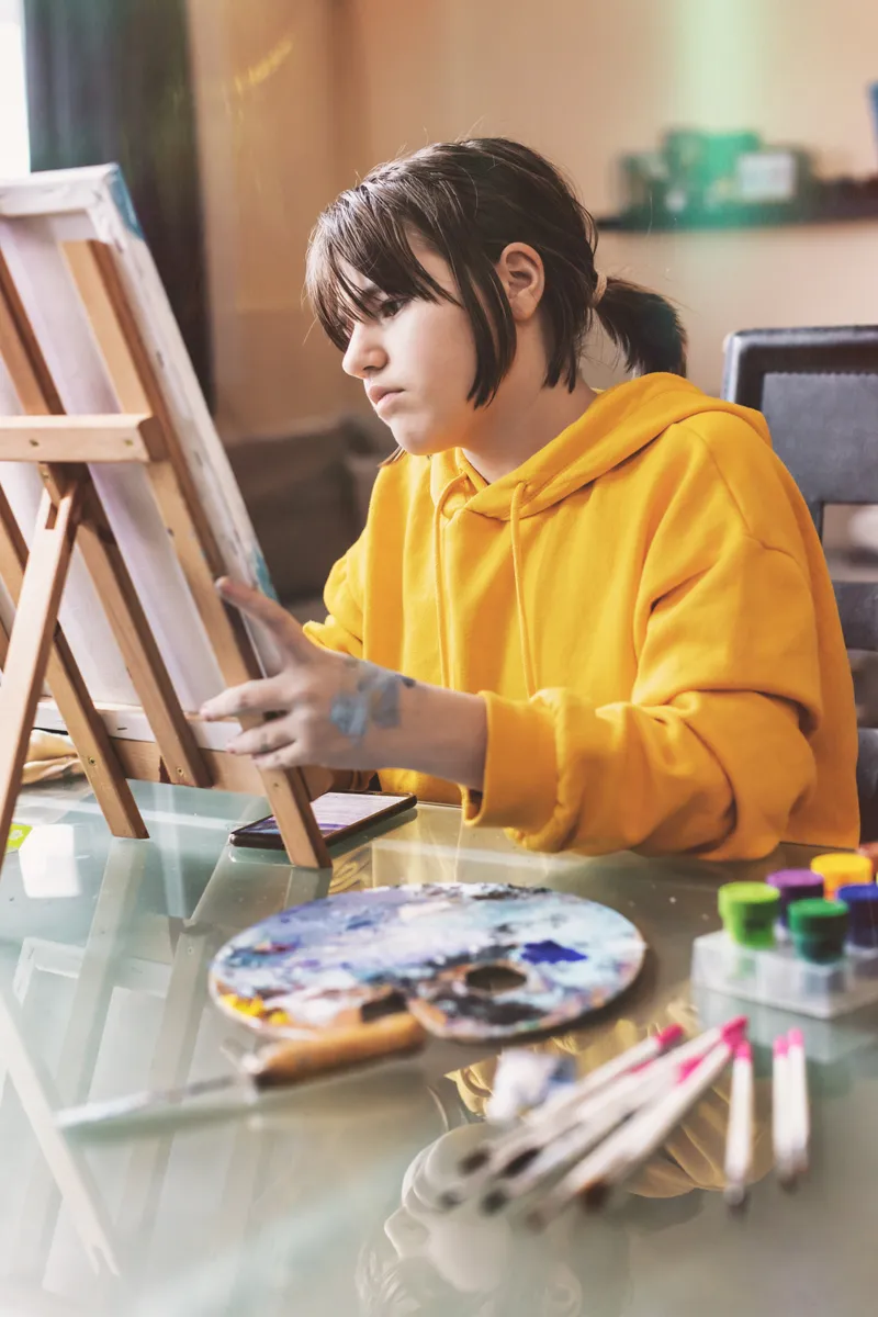 A student painting at an easel in an art studio