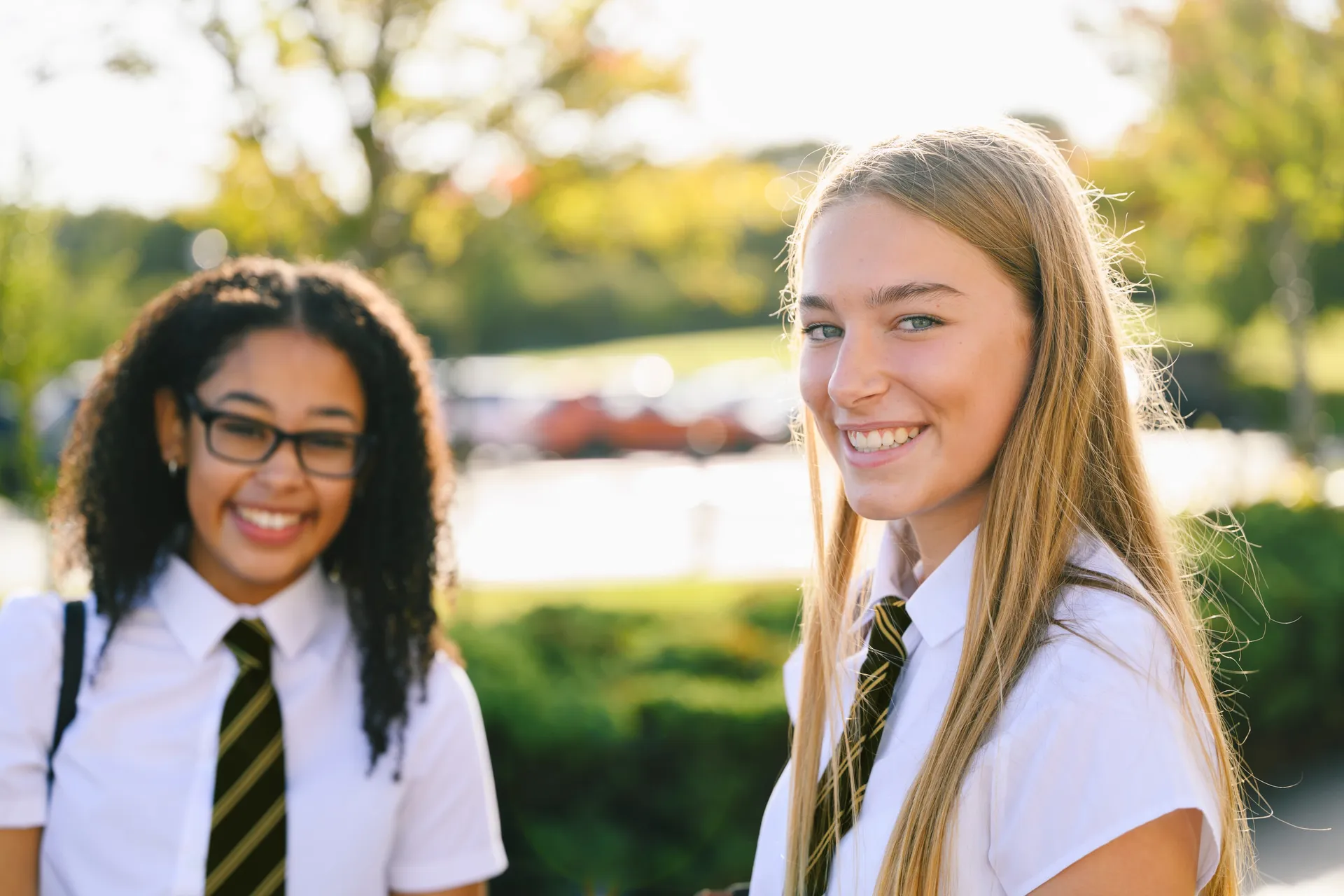 A Vaughan College student smiling warmly outdoors, in uniform with a striped tie