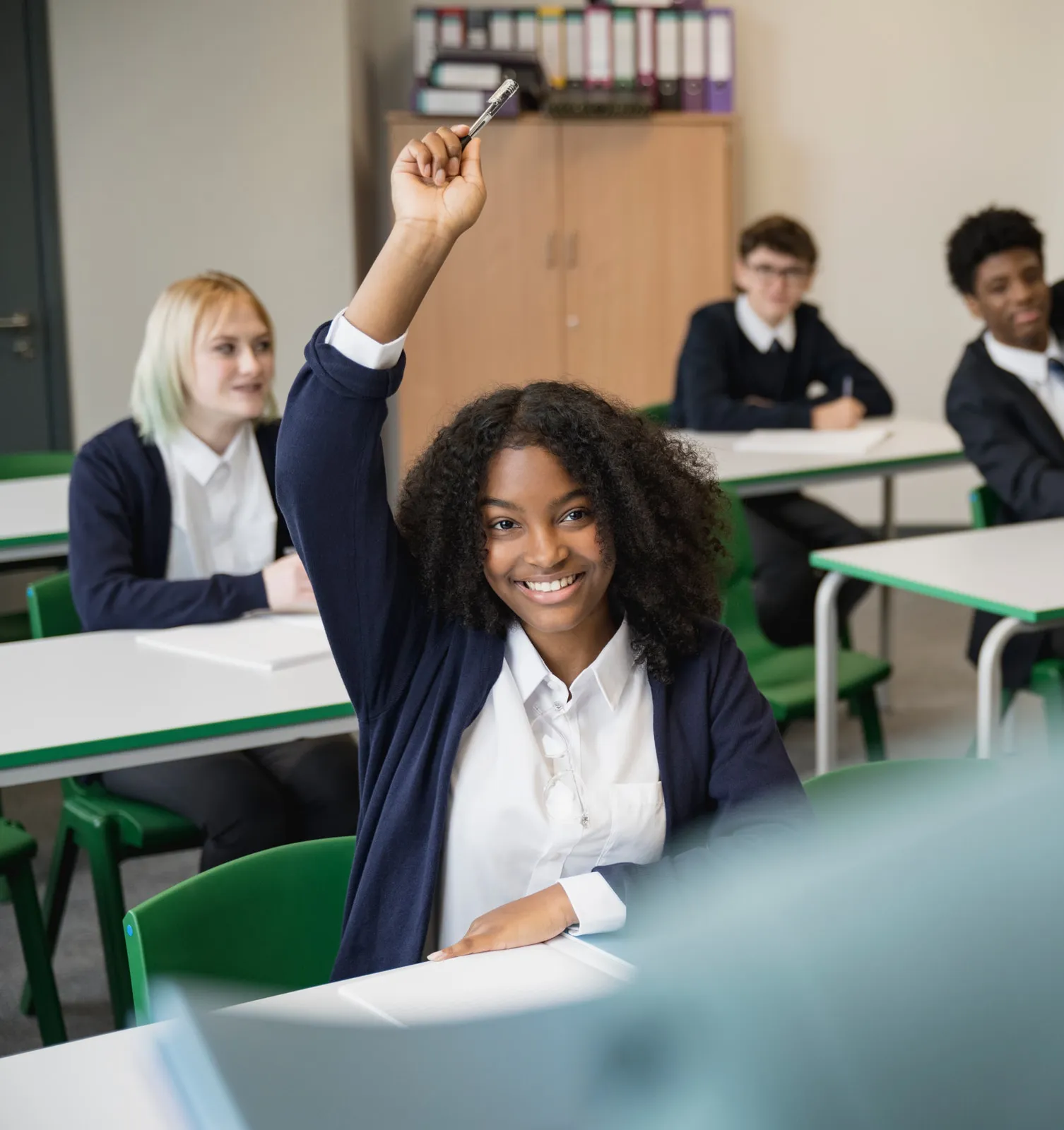A Vaughan College student raising a hand during a lively classroom discussion