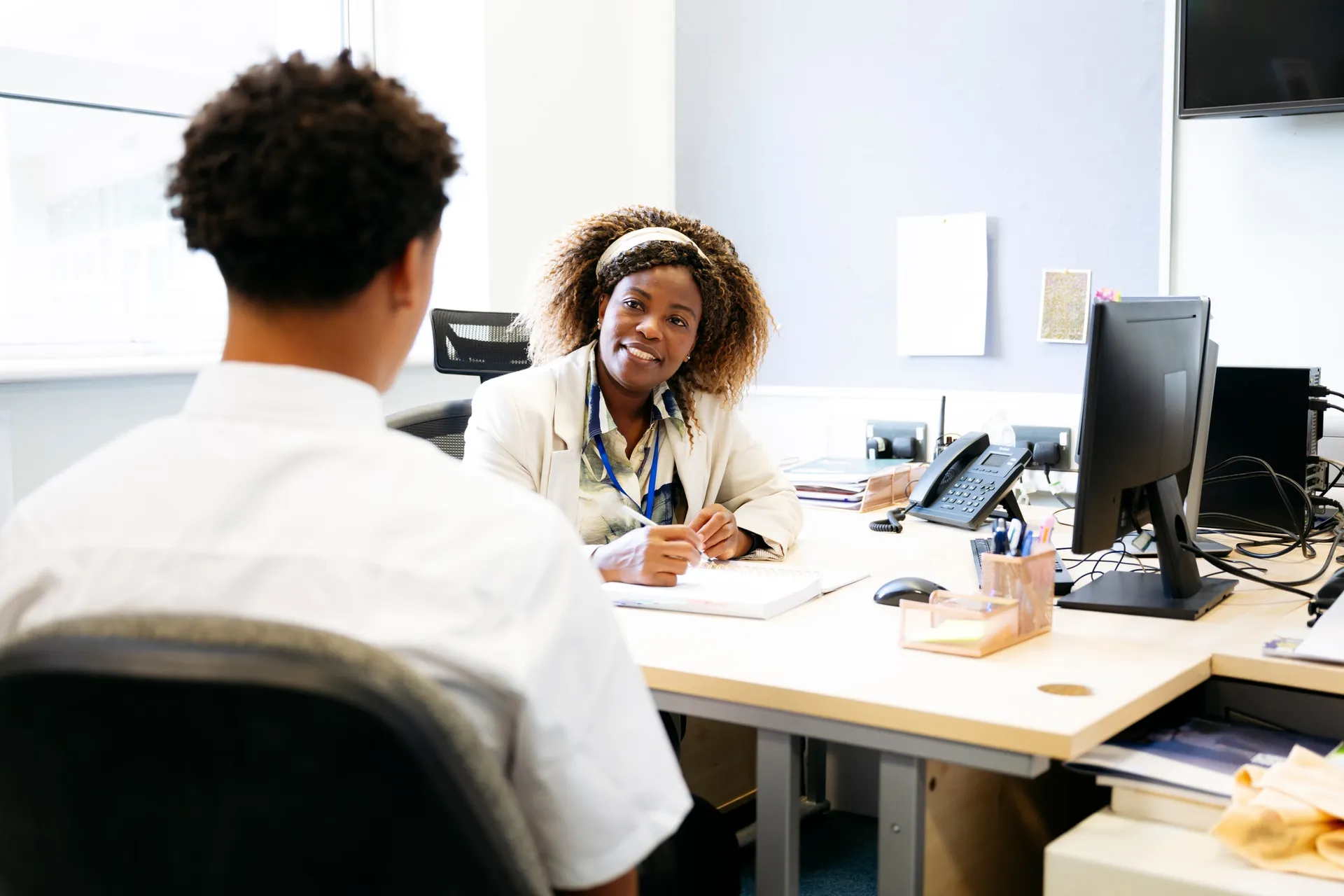 A Vaughan College staff member talking with a prospective student across an office desk