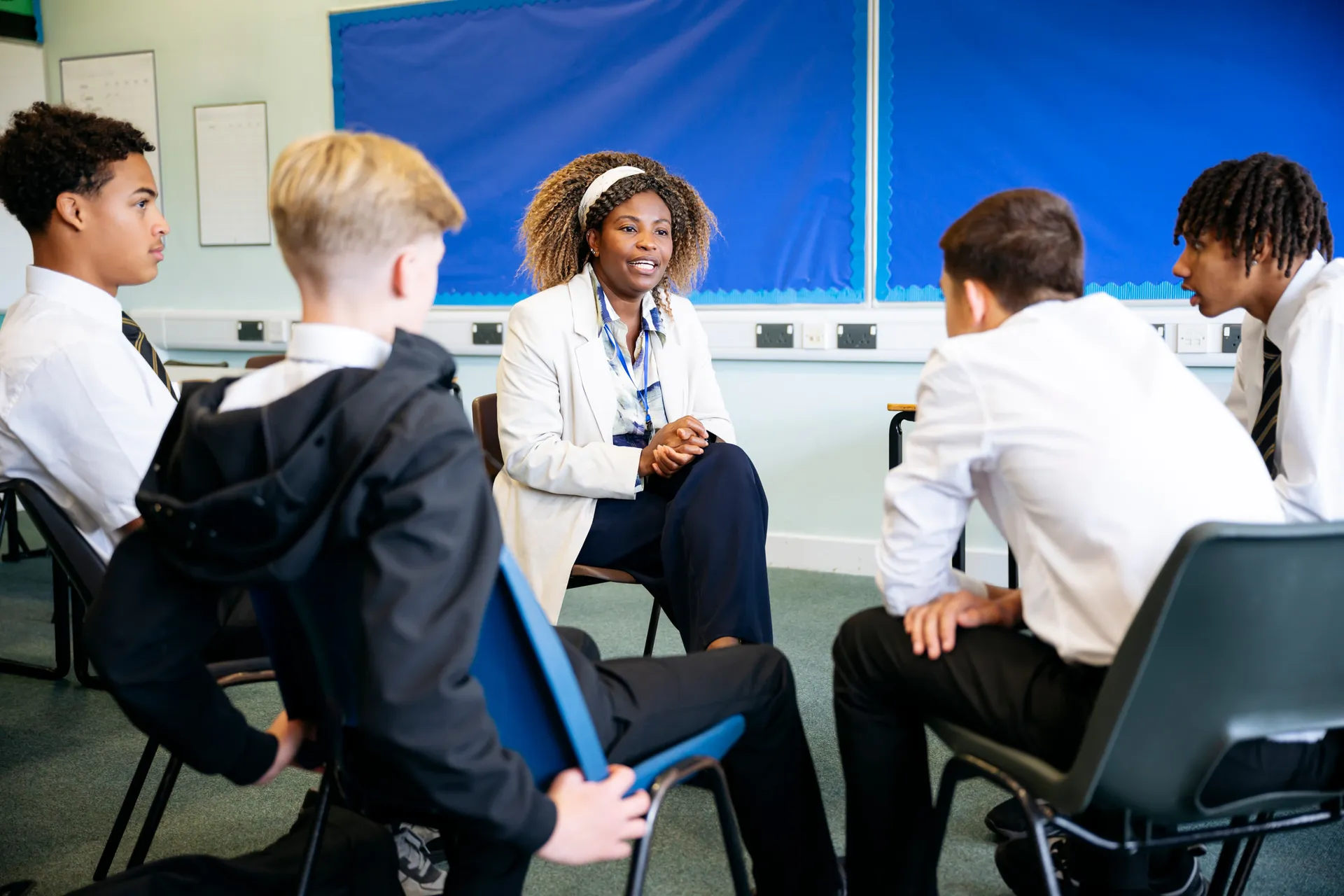 A Vaughan College support staff member sitting with a small group of students in a circle