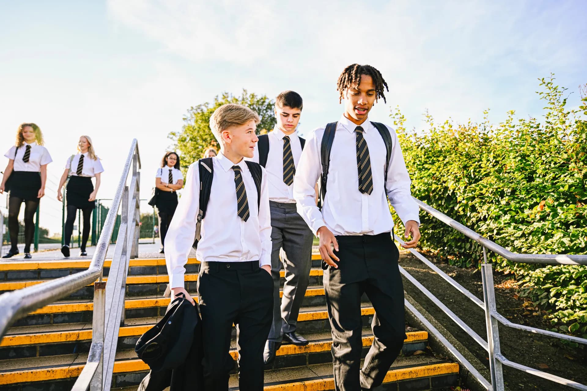Vaughan College students in uniform walking down outdoor steps on a sunny day