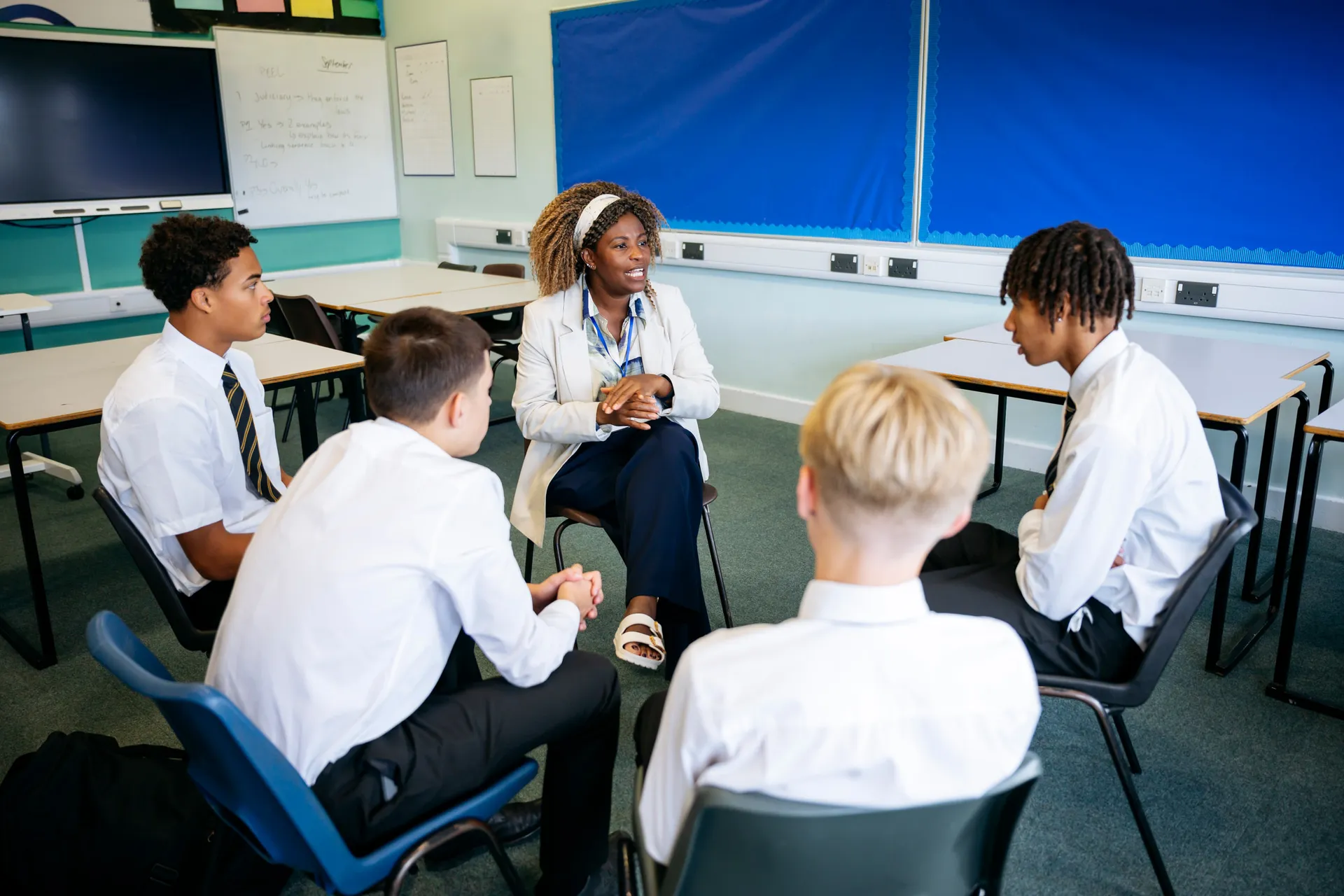 A Vaughan College support worker mentoring a small group of students seated together
