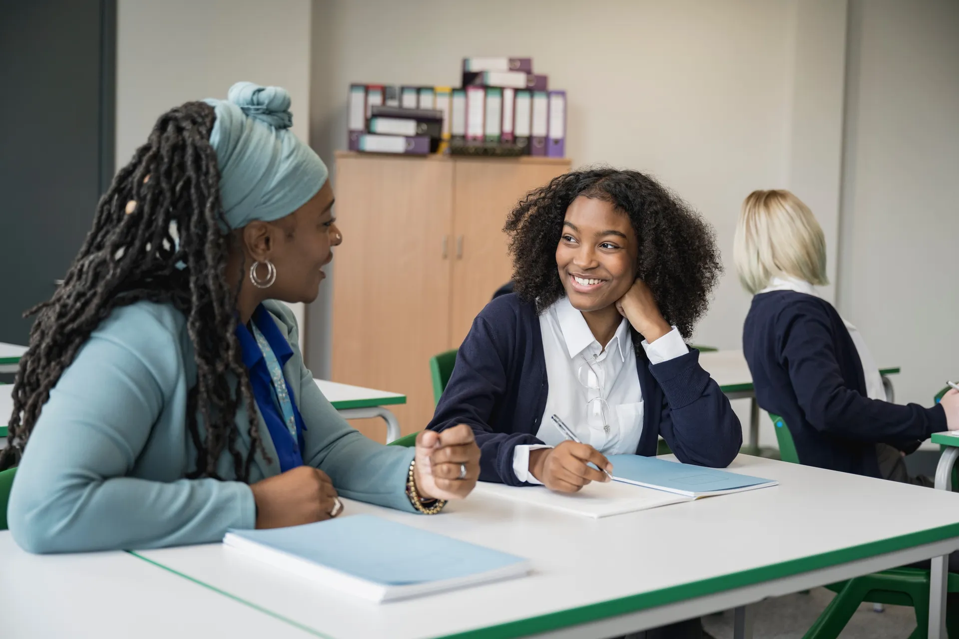 A Vaughan College teacher in a supportive one-on-one conversation with a student at a table