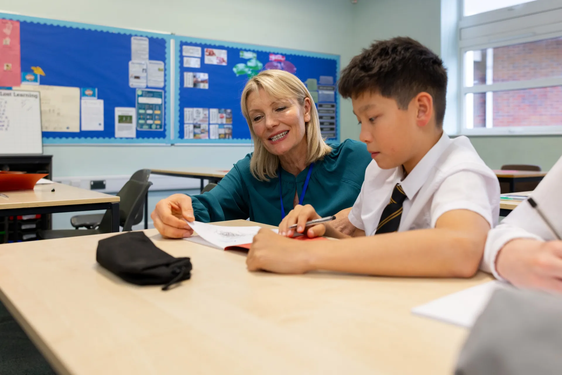 A Vaughan College teacher helping a student with work in a bright classroom