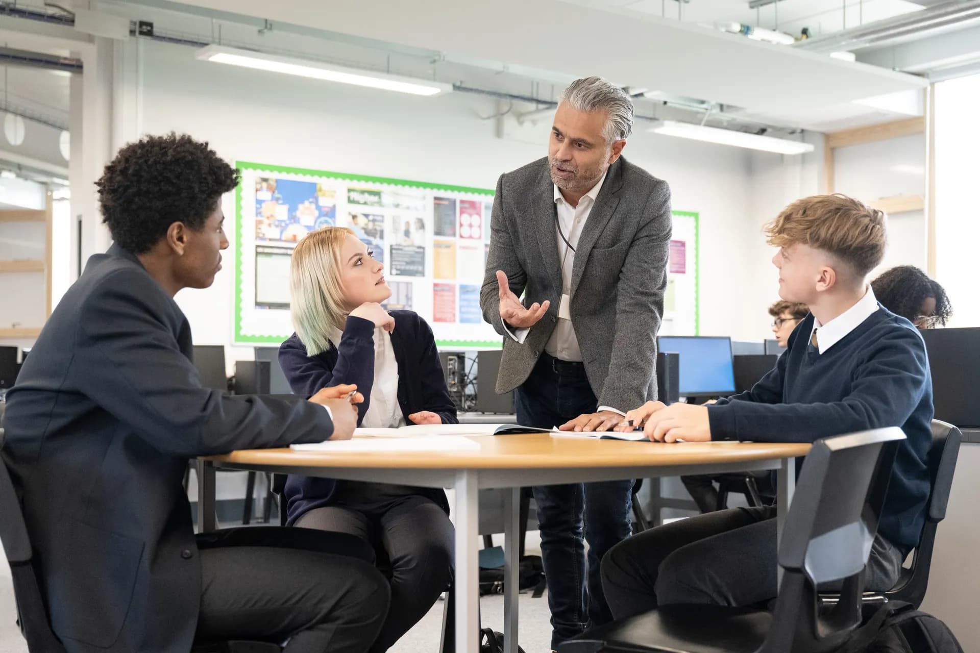 A Vaughan College teacher leading a class discussion, students in uniform listening from their desks
