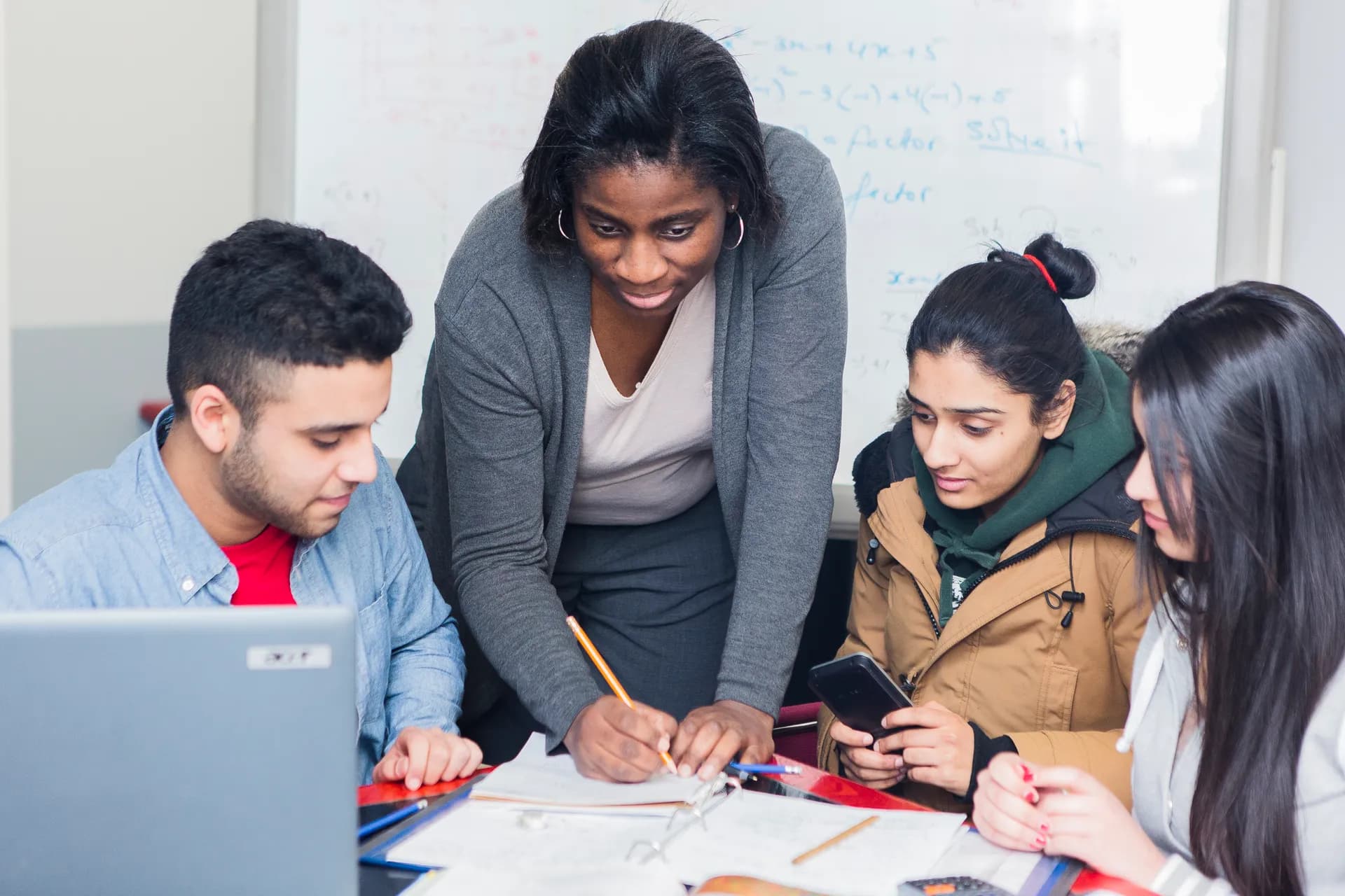 A Vaughan College teacher helping a small group of students at a classroom table