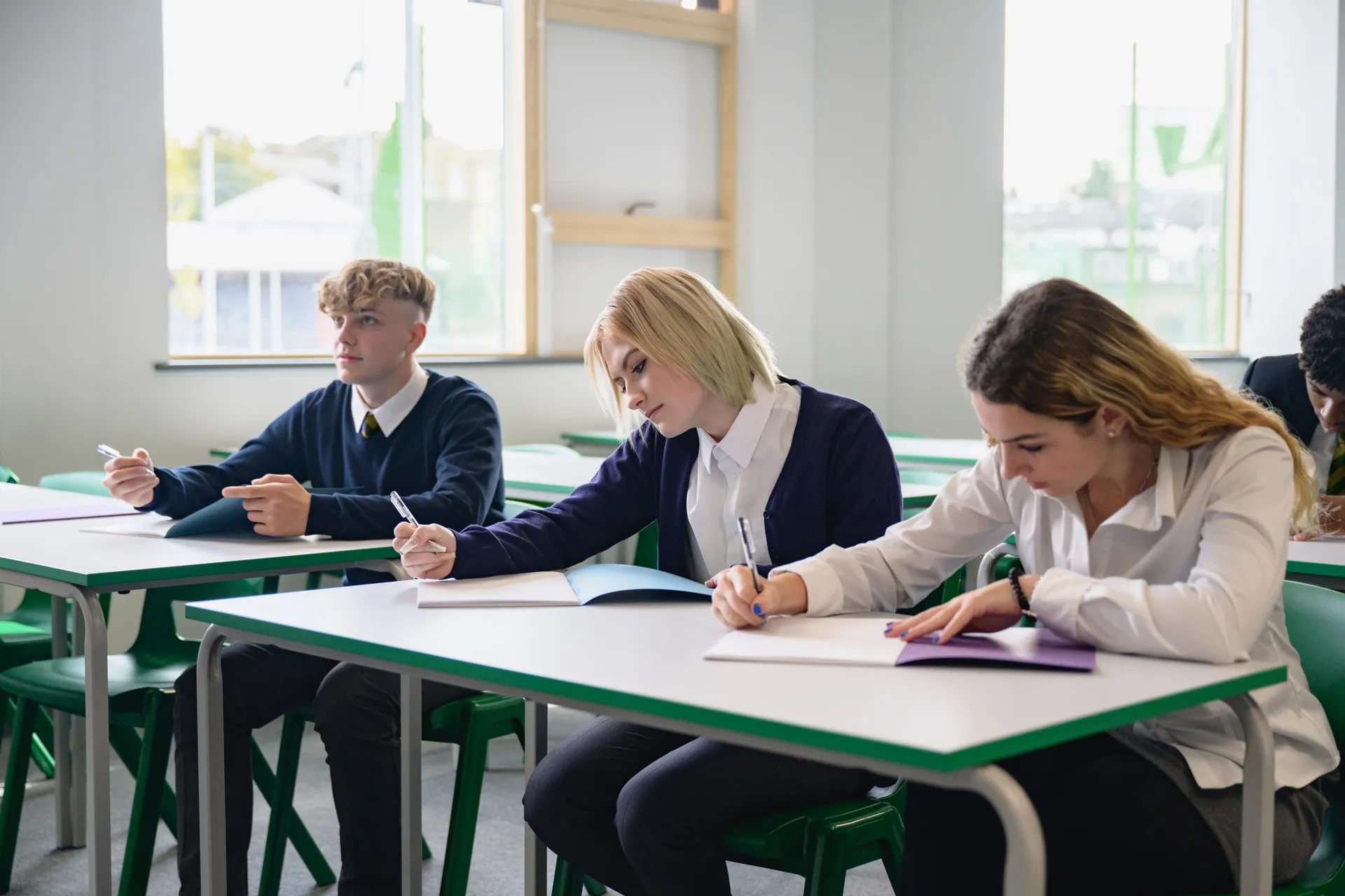Two Vaughan College students studying at their desks while a teacher assists nearby